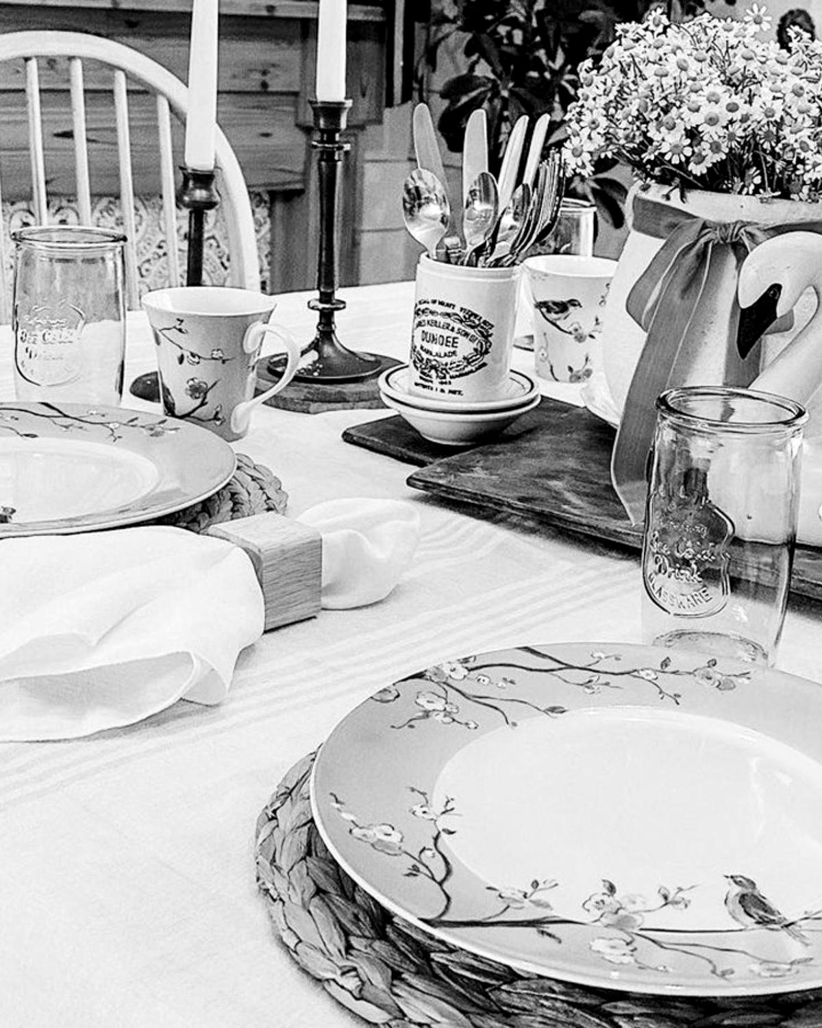 A table laid with patterned porcelain plates, a folded white napkin, glasses and candlesticks