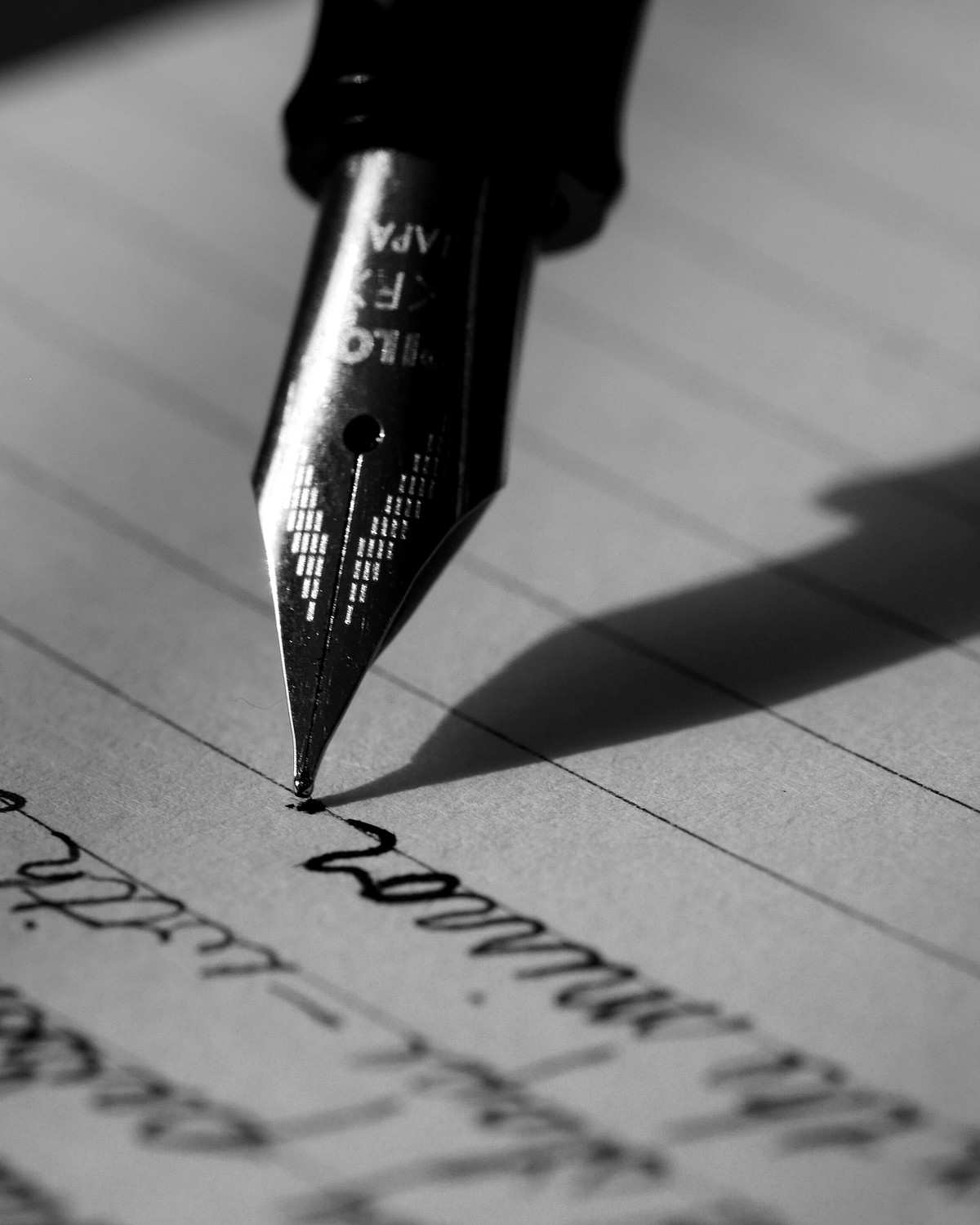 The nib of a fountain pen writing by hand on lined paper