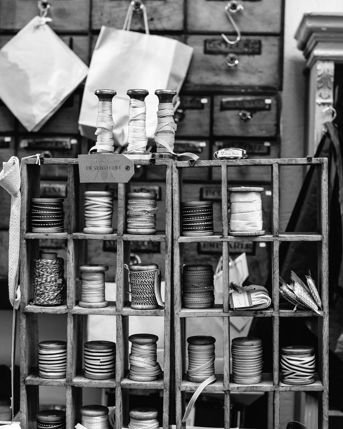 Wooden haberdashery shelves stacked with spools of thread and ribbon